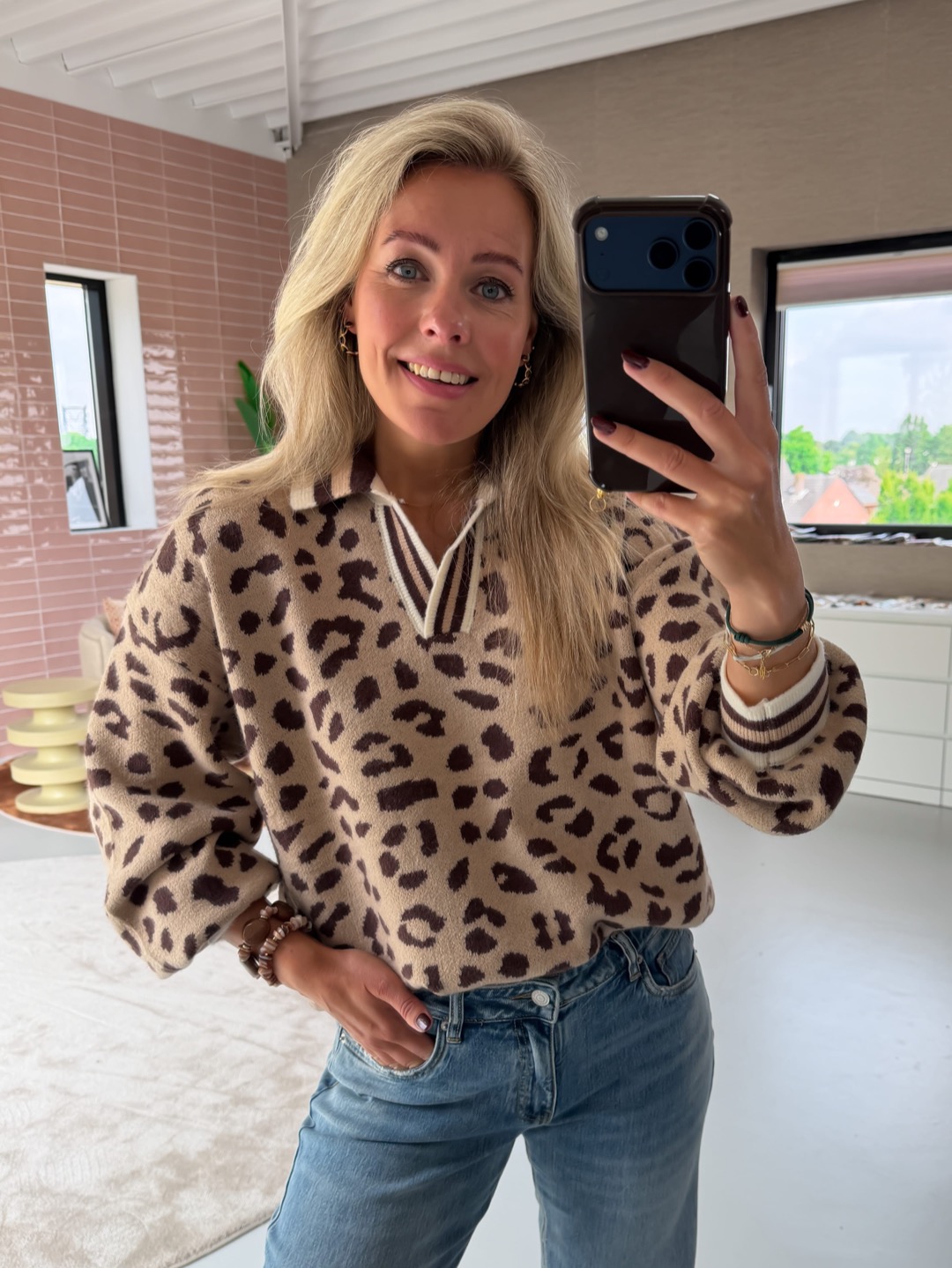 Willemijn in de Annelotte trui luipaard taupe voor de roze bakstenen muur